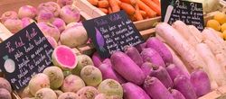 KI generiert: Das Bild zeigt eine Hand, die ein Smartphone mit einem Einkaufswagen-Symbol auf dem Bildschirm hält, vor einem Hintergrund, der Gemüsestände in einem Supermarkt zeigt. Der Hauptinhalt ist die Verbindung von digitalem Einkaufen mit der realen Einkaufssituation.