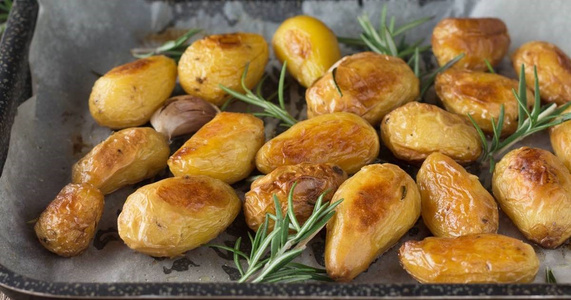 KI generiert: Das Bild zeigt ein gebackenes Gericht aus Kartoffeln und möglicherweise weiteren Zutaten wie Zwiebeln und Gemüse in einer rechteckigen Form. Eine Gabel und ein Löffel liegen darauf.