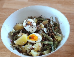 KI generiert: Das Bild zeigt ein gebackenes Gericht aus Kartoffeln und möglicherweise weiteren Zutaten wie Zwiebeln und Gemüse in einer rechteckigen Form. Eine Gabel und ein Löffel liegen darauf.
