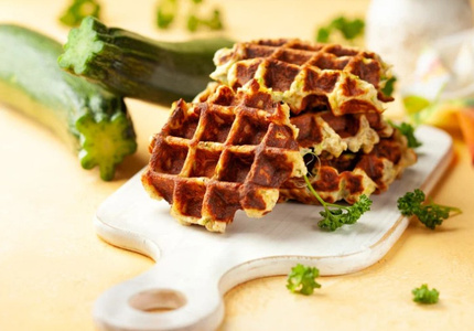 KI generiert: Das Bild zeigt ein gebackenes Gericht aus Kartoffeln und möglicherweise weiteren Zutaten wie Zwiebeln und Gemüse in einer rechteckigen Form. Eine Gabel und ein Löffel liegen darauf.