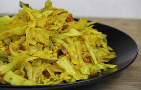 KI generiert: Das Bild zeigt ein gebackenes Gericht aus Kartoffeln und möglicherweise weiteren Zutaten wie Zwiebeln und Gemüse in einer rechteckigen Form. Eine Gabel und ein Löffel liegen darauf.