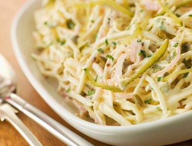 KI generiert: Das Bild zeigt ein gebackenes Gericht aus Kartoffeln und möglicherweise weiteren Zutaten wie Zwiebeln und Gemüse in einer rechteckigen Form. Eine Gabel und ein Löffel liegen darauf.
