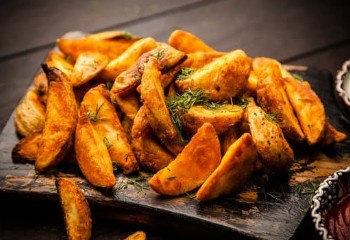KI generiert: Das Bild zeigt ein gebackenes Gericht aus Kartoffeln und möglicherweise weiteren Zutaten wie Zwiebeln und Gemüse in einer rechteckigen Form. Eine Gabel und ein Löffel liegen darauf.
