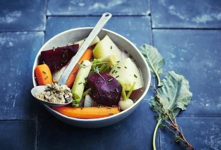 KI generiert: Das Bild zeigt ein gebackenes Gericht aus Kartoffeln und möglicherweise weiteren Zutaten wie Zwiebeln und Gemüse in einer rechteckigen Form. Eine Gabel und ein Löffel liegen darauf.