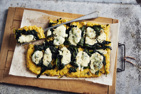 KI generiert: Das Bild zeigt ein gebackenes Gericht aus Kartoffeln und möglicherweise weiteren Zutaten wie Zwiebeln und Gemüse in einer rechteckigen Form. Eine Gabel und ein Löffel liegen darauf.