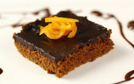 KI generiert: Das Bild zeigt ein gebackenes Gericht aus Kartoffeln und möglicherweise weiteren Zutaten wie Zwiebeln und Gemüse in einer rechteckigen Form. Eine Gabel und ein Löffel liegen darauf.