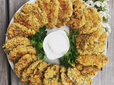 KI generiert: Das Bild zeigt ein gebackenes Gericht aus Kartoffeln und möglicherweise weiteren Zutaten wie Zwiebeln und Gemüse in einer rechteckigen Form. Eine Gabel und ein Löffel liegen darauf.