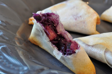 KI generiert: Das Bild zeigt ein gebackenes Gericht aus Kartoffeln und möglicherweise weiteren Zutaten wie Zwiebeln und Gemüse in einer rechteckigen Form. Eine Gabel und ein Löffel liegen darauf.