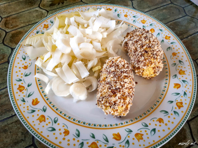 KI generiert: Das Bild zeigt ein gebackenes Gericht aus Kartoffeln und möglicherweise weiteren Zutaten wie Zwiebeln und Gemüse in einer rechteckigen Form. Eine Gabel und ein Löffel liegen darauf.